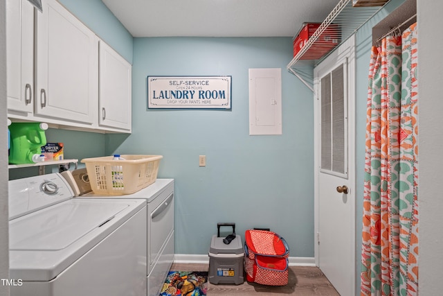 clothes washing area featuring wood-type flooring, cabinets, electric panel, and washing machine and dryer