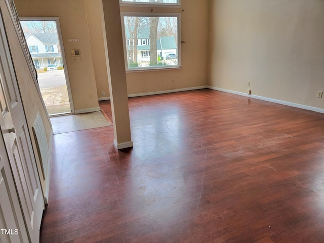 empty room with a healthy amount of sunlight and dark hardwood / wood-style floors