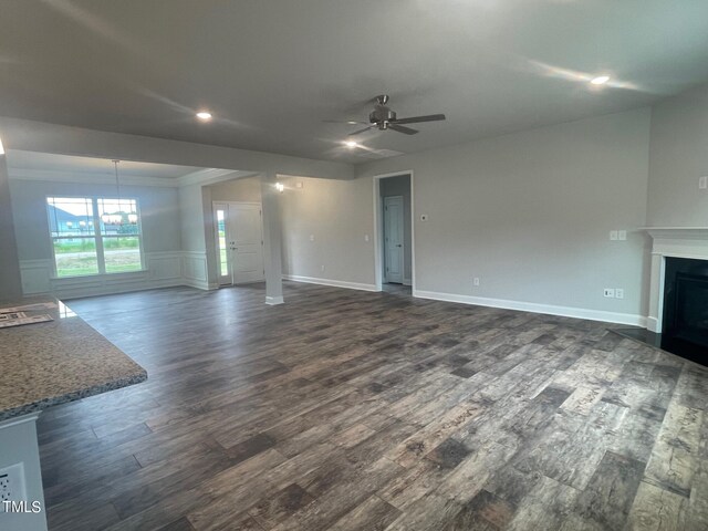 unfurnished living room with ornamental molding, dark hardwood / wood-style floors, and ceiling fan with notable chandelier