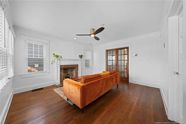 living room featuring a fireplace, ceiling fan, french doors, dark wood-type flooring, and crown molding