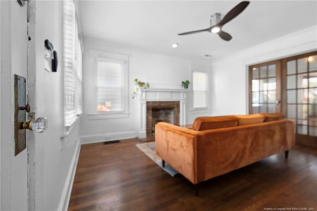 living room with a brick fireplace, ceiling fan, and dark hardwood / wood-style floors