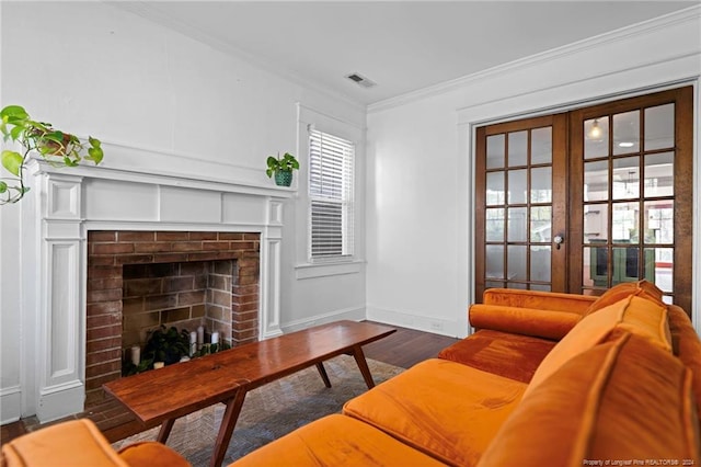 living room with french doors, a brick fireplace, dark wood-type flooring, and ornamental molding