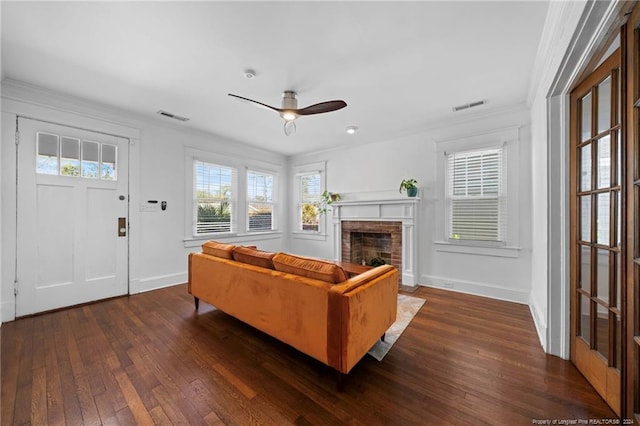 living room with dark hardwood / wood-style flooring, ceiling fan, a brick fireplace, and a wealth of natural light