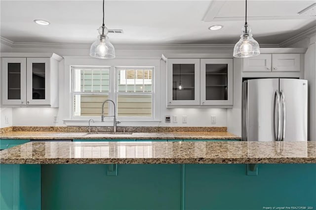 kitchen featuring pendant lighting, sink, stainless steel refrigerator, and white cabinets