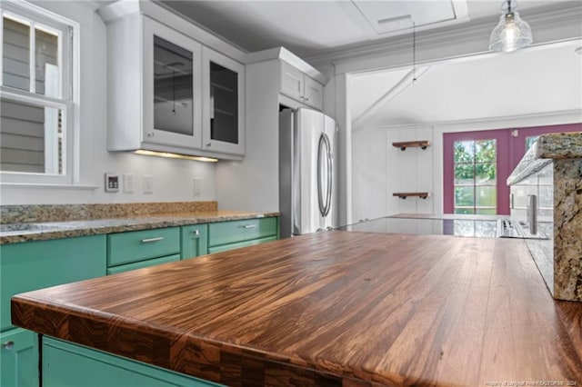 kitchen featuring stainless steel refrigerator, hardwood / wood-style floors, green cabinetry, decorative light fixtures, and wood counters