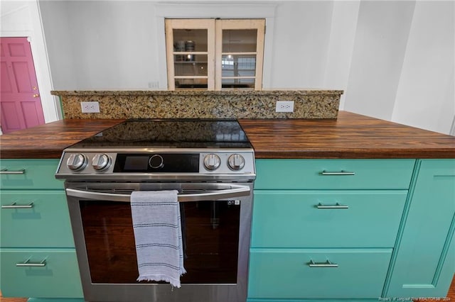 kitchen with dark stone counters, electric stove, and green cabinets