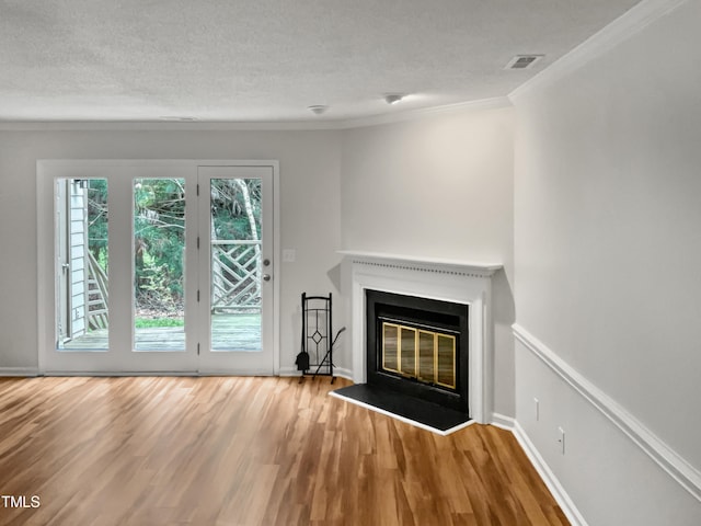 unfurnished living room with plenty of natural light, a textured ceiling, crown molding, and light wood-type flooring