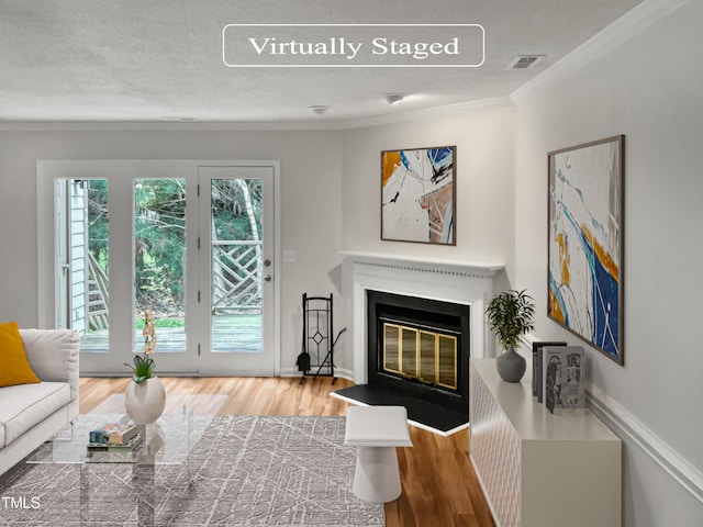 living room featuring ornamental molding, light hardwood / wood-style floors, and a textured ceiling