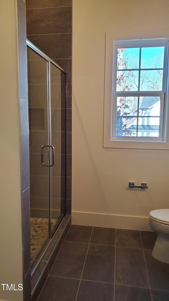 bathroom with a stall shower, baseboards, and tile patterned floors