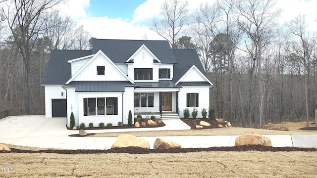 modern farmhouse style home featuring brick siding, a chimney, concrete driveway, a standing seam roof, and metal roof