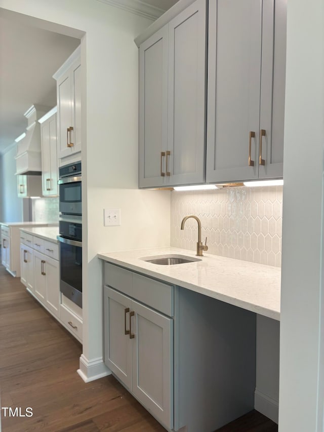 kitchen featuring custom exhaust hood, sink, dark wood-type flooring, stainless steel double oven, and crown molding