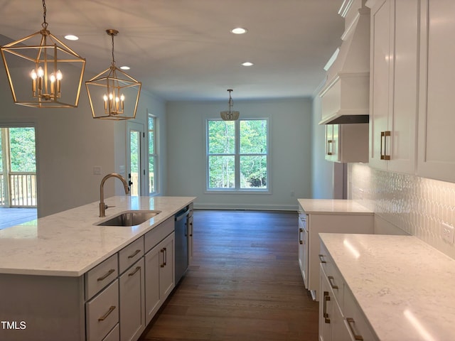 kitchen with decorative light fixtures, a kitchen island with sink, sink, and a wealth of natural light