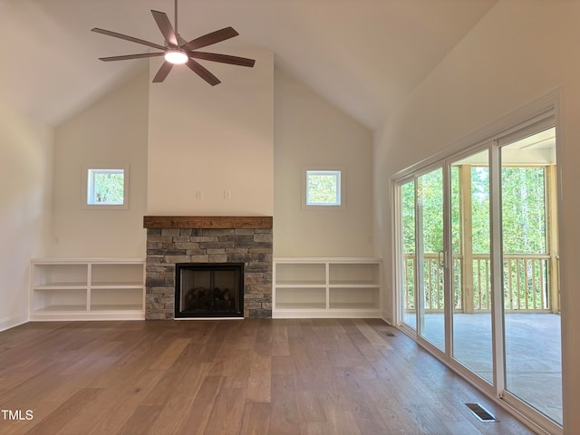 unfurnished living room with high vaulted ceiling, wood-type flooring, ceiling fan, and a stone fireplace