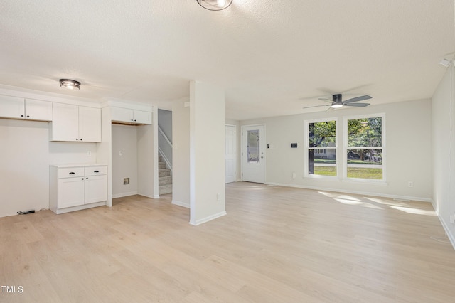 unfurnished living room featuring ceiling fan, a textured ceiling, and light hardwood / wood-style flooring