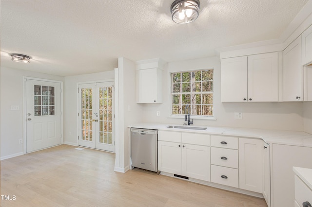 kitchen with light hardwood / wood-style flooring, white cabinets, stainless steel dishwasher, and sink