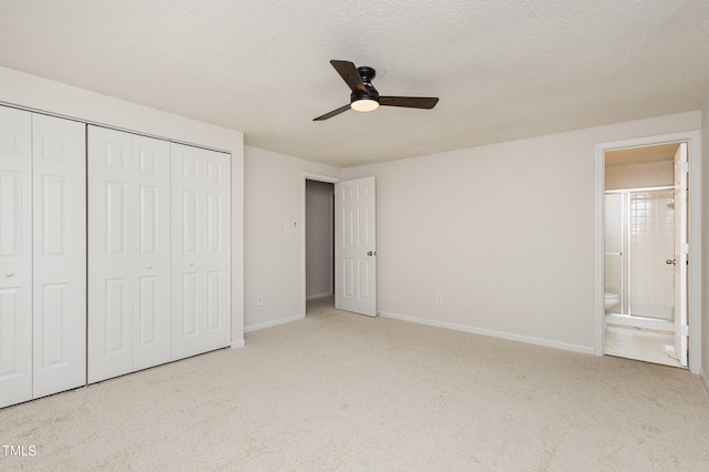 unfurnished bedroom with connected bathroom, a textured ceiling, light colored carpet, and ceiling fan