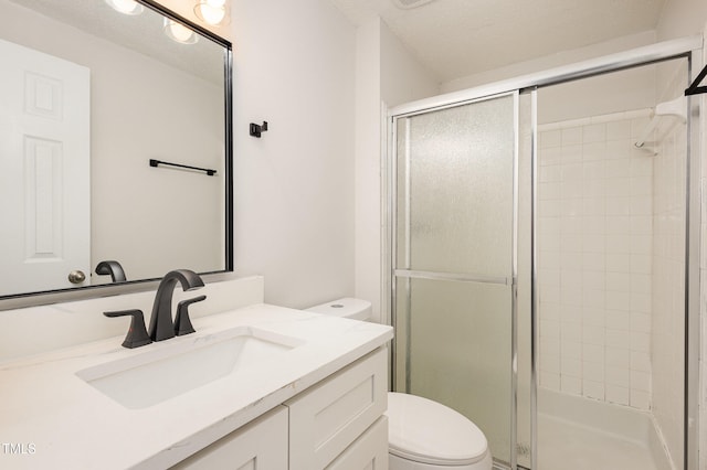 bathroom with a shower with door, vanity, a textured ceiling, and toilet