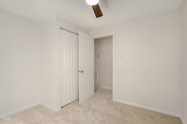 unfurnished bedroom featuring light carpet, a closet, and ceiling fan