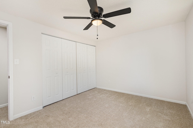 unfurnished bedroom featuring light carpet, a closet, and ceiling fan