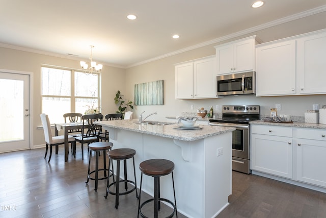 kitchen with appliances with stainless steel finishes, an island with sink, a notable chandelier, decorative light fixtures, and dark hardwood / wood-style floors