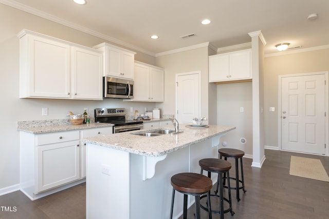 kitchen with dark hardwood / wood-style flooring, white cabinets, stainless steel appliances, and a kitchen island with sink