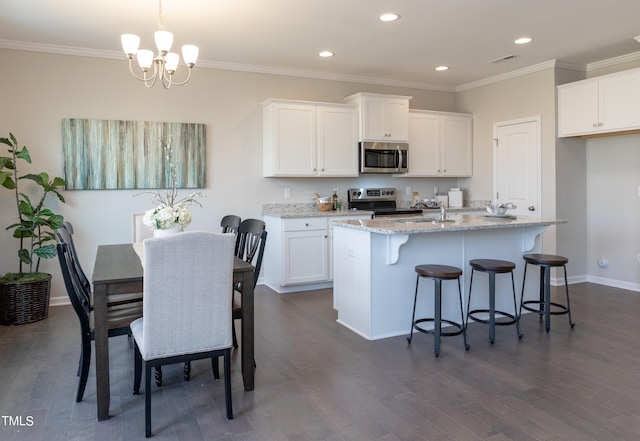 kitchen featuring a notable chandelier, stainless steel appliances, white cabinets, a center island with sink, and dark hardwood / wood-style flooring