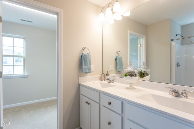 bathroom with dual sinks, large vanity, and a shower