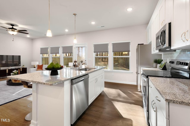 kitchen with white cabinetry, stainless steel appliances, decorative light fixtures, and sink