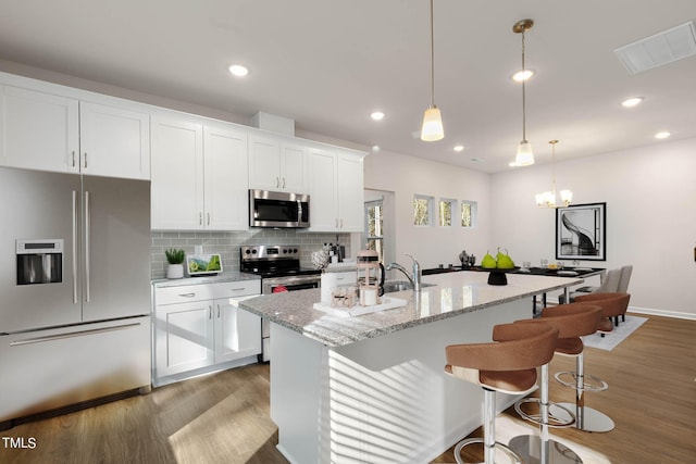 kitchen featuring a kitchen island with sink, white cabinets, and appliances with stainless steel finishes