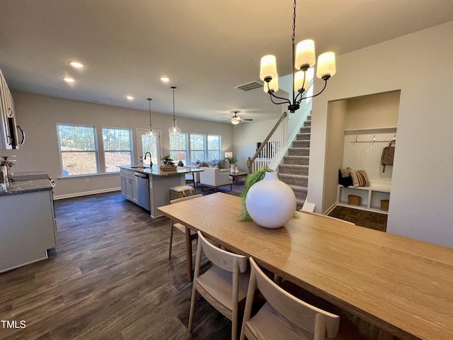 dining area with dark hardwood / wood-style flooring and ceiling fan with notable chandelier