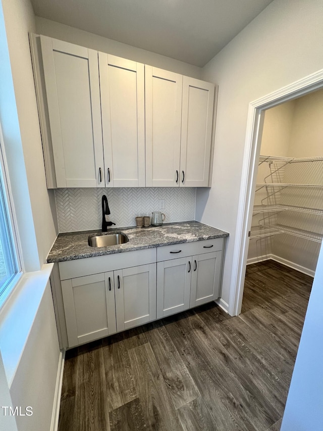 bar with white cabinetry, sink, backsplash, and dark hardwood / wood-style flooring