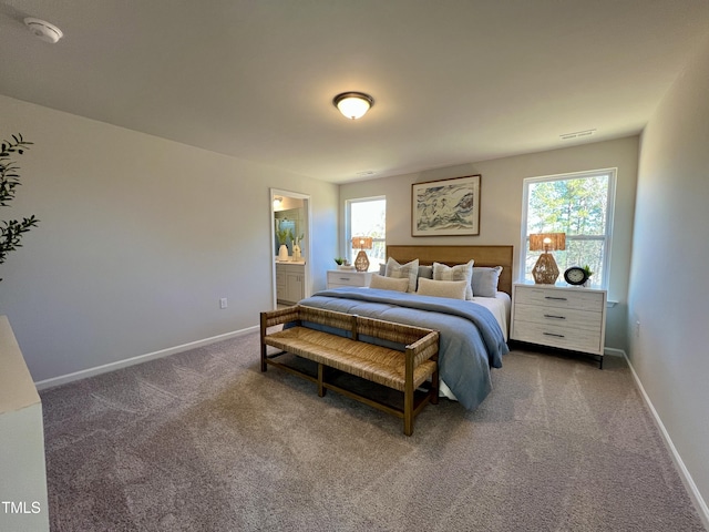 bedroom with connected bathroom and dark colored carpet