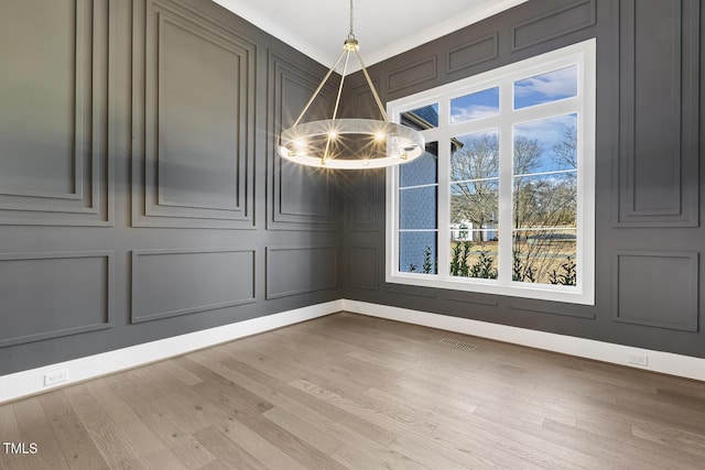 unfurnished dining area featuring hardwood / wood-style flooring, an inviting chandelier, and crown molding