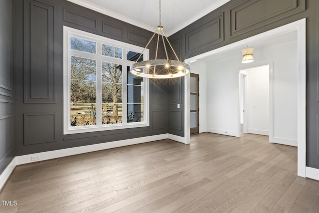 unfurnished dining area with hardwood / wood-style floors, a notable chandelier, and crown molding