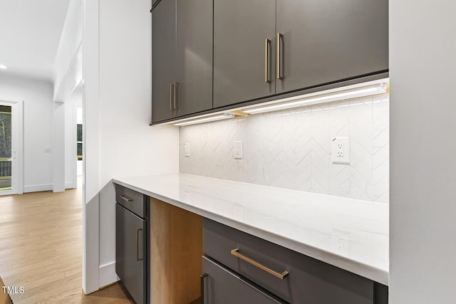 kitchen featuring light stone countertops, backsplash, and light hardwood / wood-style flooring