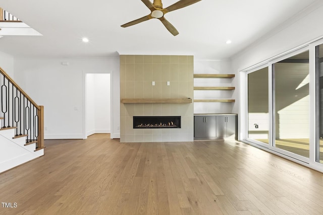 unfurnished living room featuring a tile fireplace, light hardwood / wood-style flooring, ceiling fan, and ornamental molding