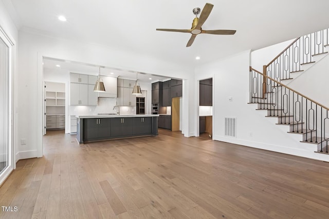 unfurnished living room with ceiling fan, hardwood / wood-style floors, and crown molding