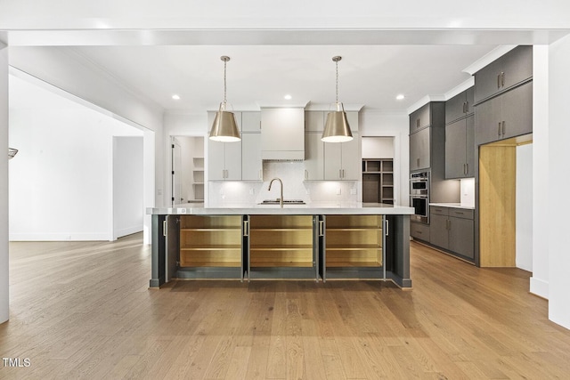 kitchen featuring pendant lighting, gray cabinetry, sink, and a large island with sink