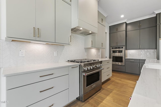 kitchen featuring stainless steel appliances, backsplash, light wood-type flooring, gray cabinets, and ornamental molding