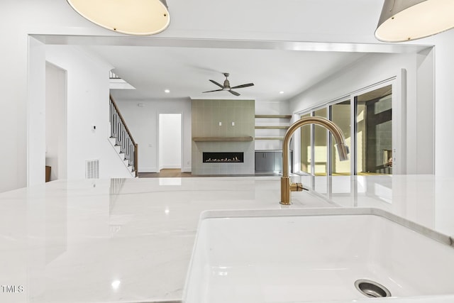 interior details featuring a tile fireplace, ceiling fan, and sink