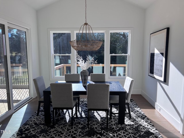 dining room featuring a notable chandelier, wood-type flooring, and lofted ceiling