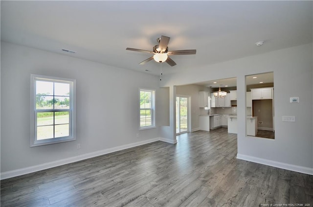 unfurnished living room with hardwood / wood-style floors and ceiling fan with notable chandelier