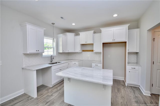 kitchen with white cabinetry, sink, light hardwood / wood-style floors, and a kitchen island