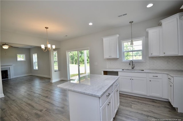 kitchen with a kitchen island, sink, white cabinets, and decorative backsplash