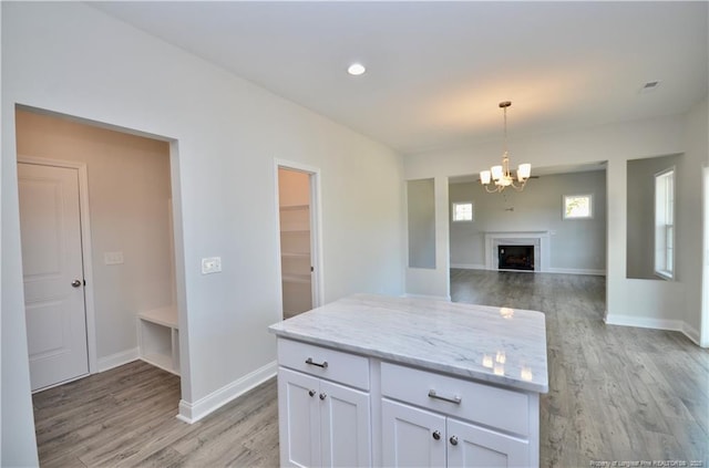 kitchen with white cabinetry, light stone countertops, a chandelier, and light wood-type flooring