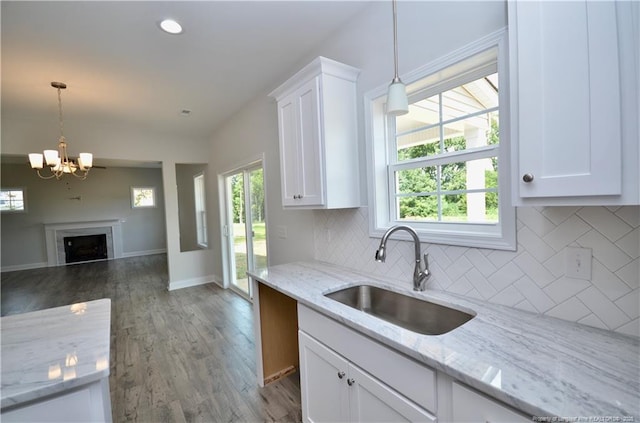 kitchen with white cabinetry, sink, and light stone counters