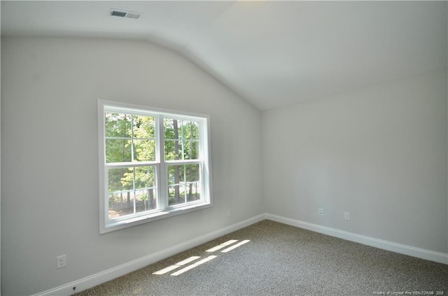 carpeted empty room featuring vaulted ceiling