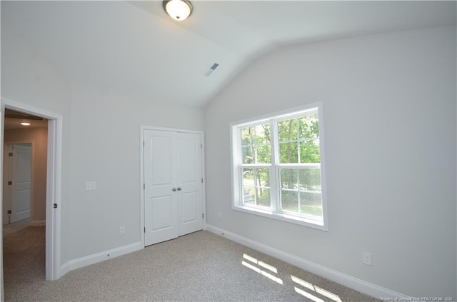 unfurnished bedroom with lofted ceiling, light carpet, and a closet