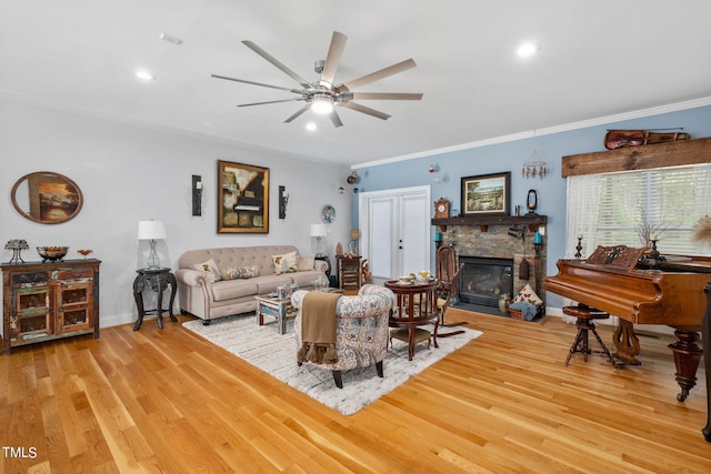 living room with ornamental molding, ceiling fan, light wood-type flooring, and a fireplace