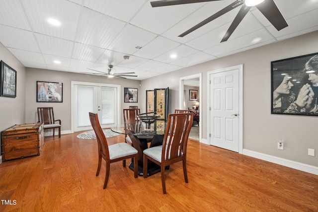 dining area featuring french doors, light hardwood / wood-style floors, a drop ceiling, and ceiling fan